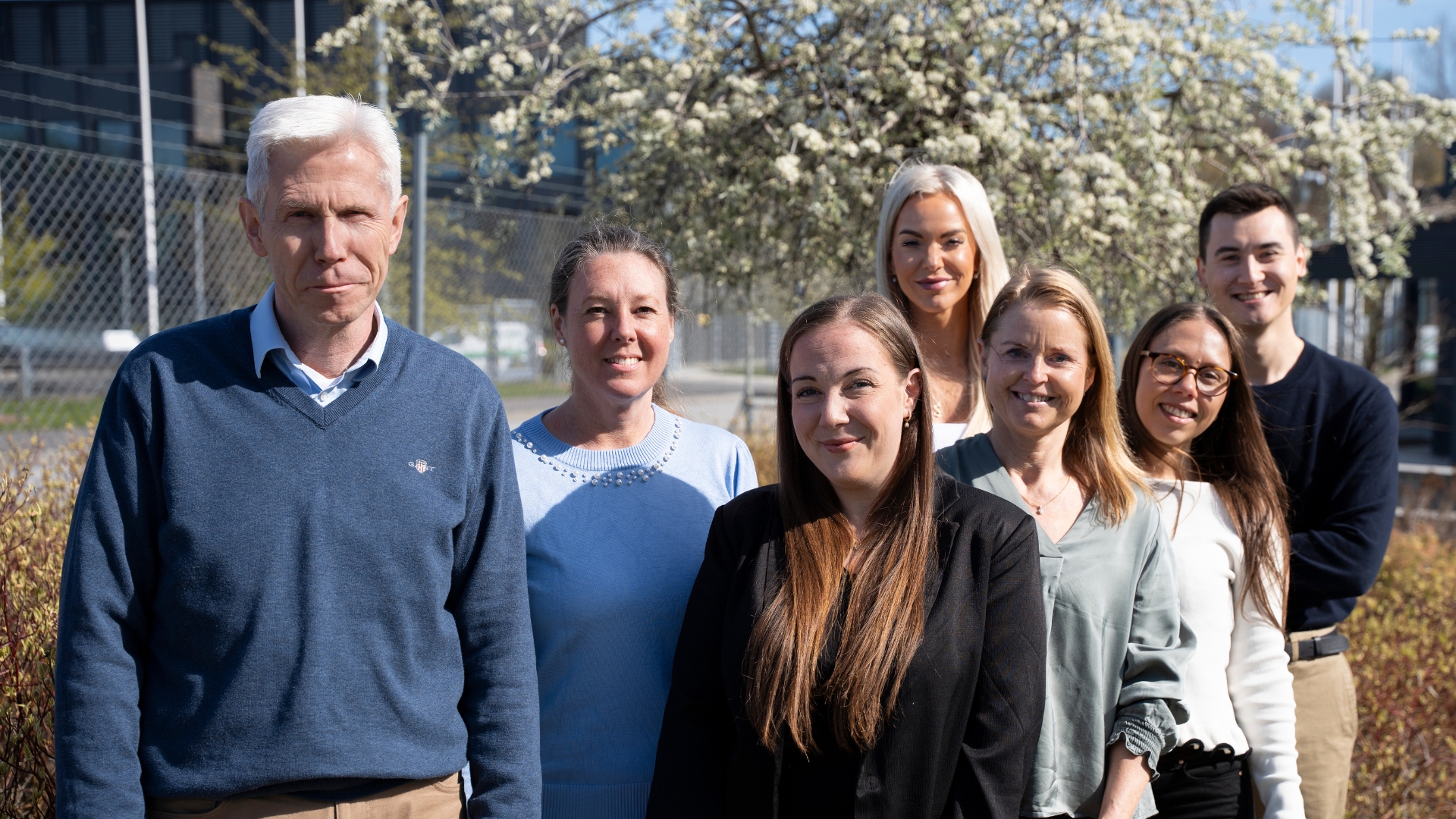 Sandberg Developments ekonomiteam står glatt uppradade framför ett magnoliaträd i Sandberg Valley. 
