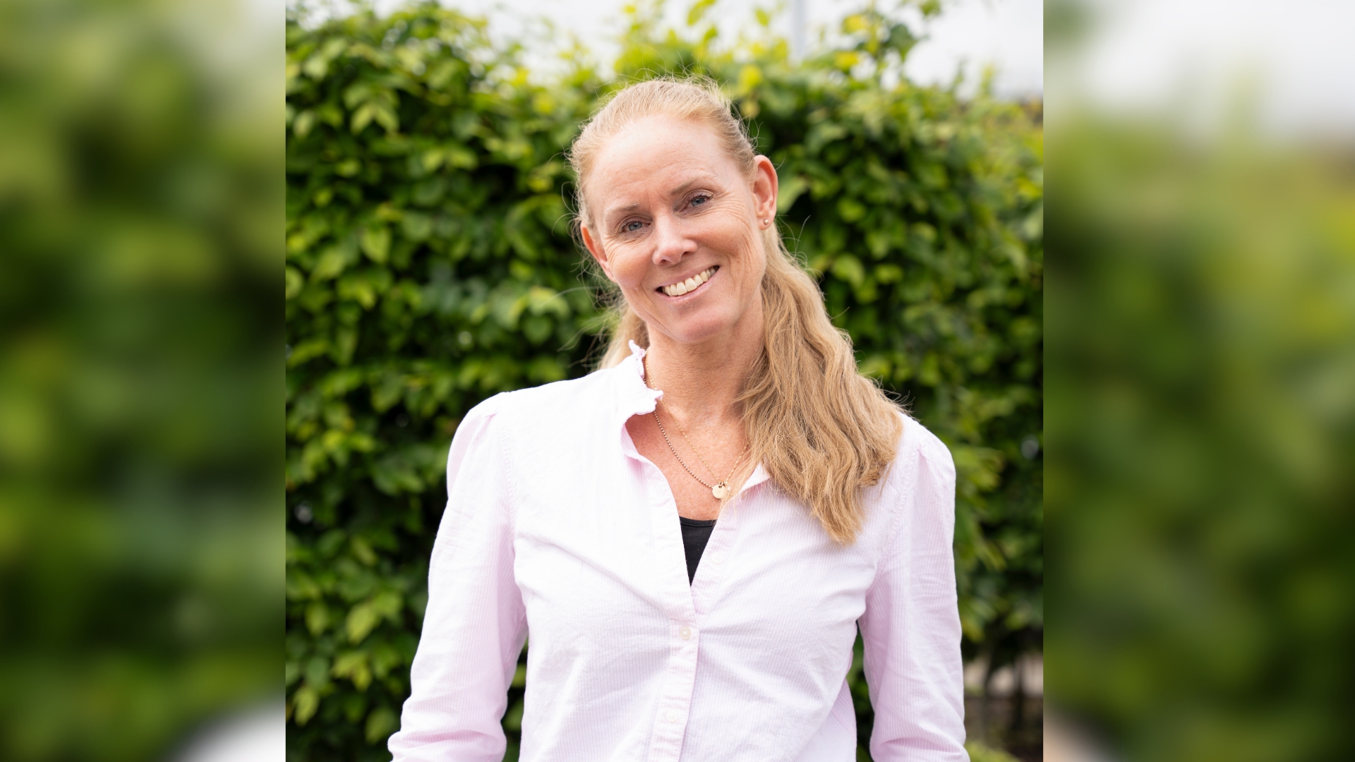 Porträttbild på Josefine Hardebo, inköpare och Facility Coordinator på Sandberg Development, framför en grönskande buske. 
