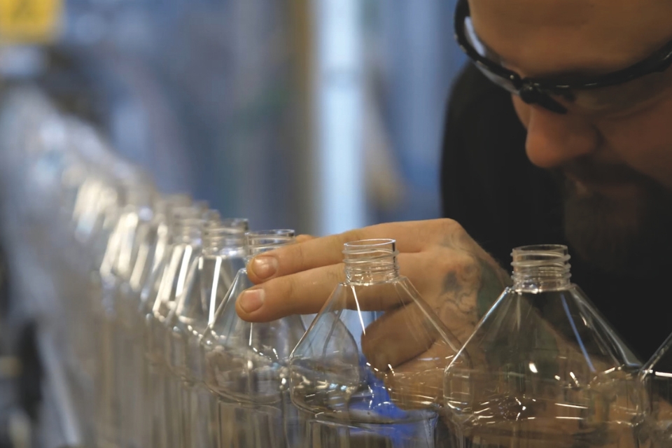 Man med skyddsglasögon står vid Rekals produktionsled med förpackningar till deras rengöringsprodukter. 