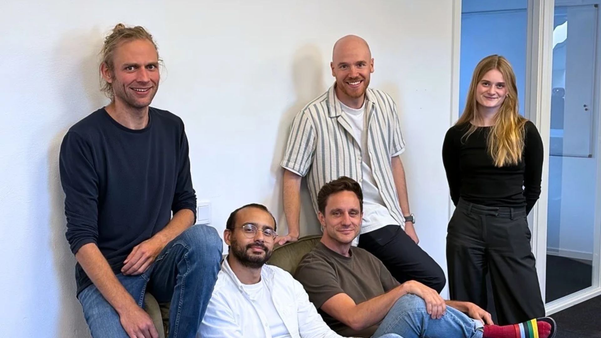 The PluvioFlow team, sitting on a couch and standing beside it, smiling at the camera.