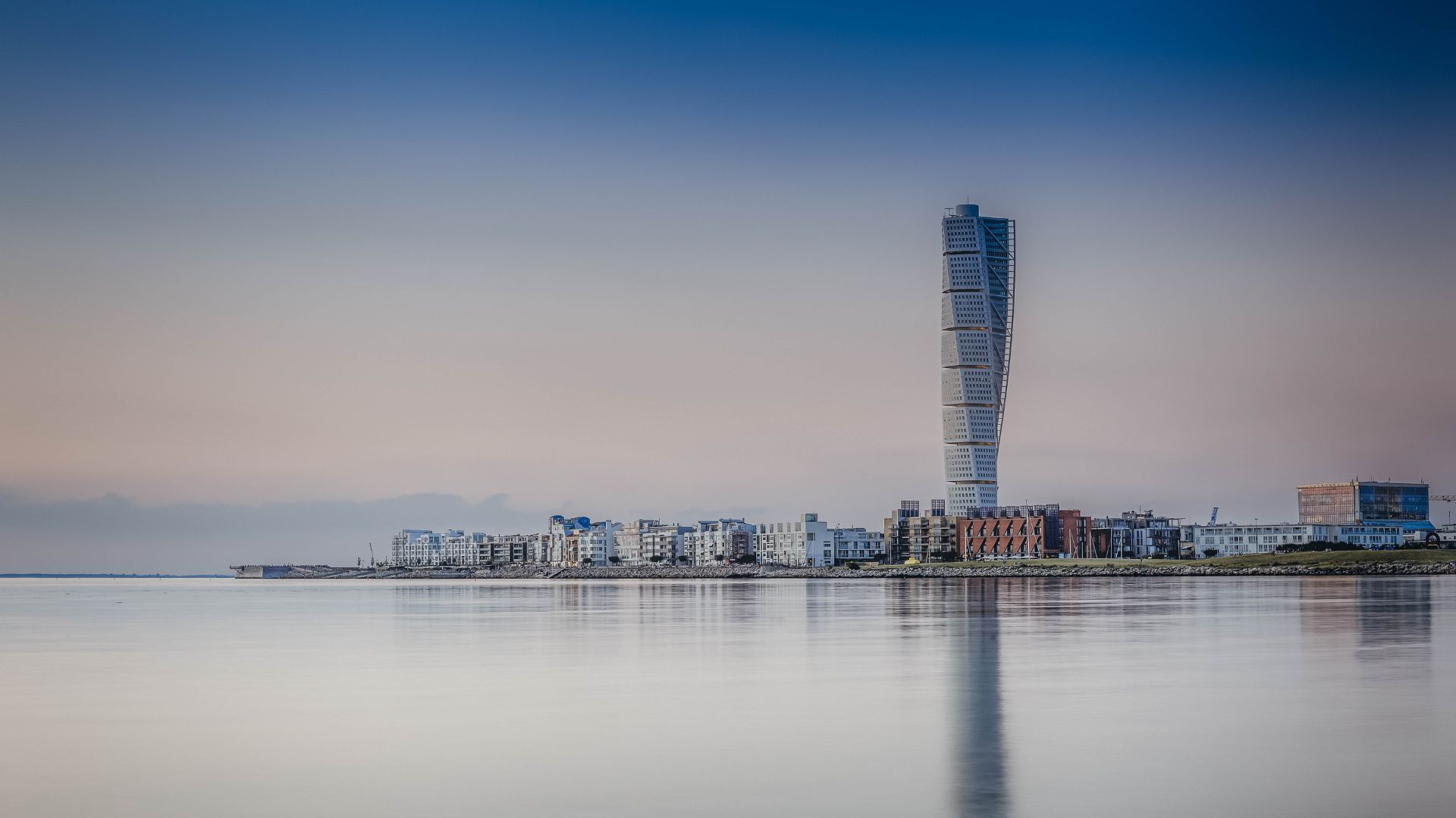 Turning Torso i Västra hamnen i Malmö stad reflekteras mot vattnet vid solnedgången